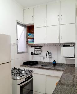 een witte keuken met een fornuis en een wastafel bij Apartamento bem localizado. in Praia Grande