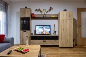 a living room with a television in a wooden entertainment center at Apartman Tune 