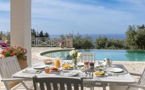 a table with food on it with a view of a pool at Villa Kalithea in Vlachopoulátika