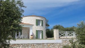a house with a stone wall and a fence at Villa Kalithea in Vlachopoulátika