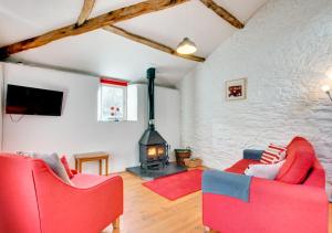 a living room with two red chairs and a fireplace at Bovey Cottage in Broadhempston