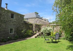 a garden with two chairs and a table in front of a building at Bovey Cottage in Broadhempston