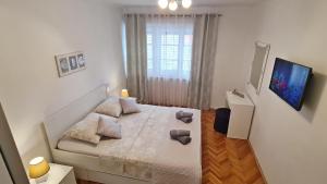 a small white bedroom with a bed and a window at Apartment Sara Poljud in Split