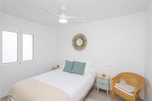a white bedroom with a bed and a chair at Sea Views Private Terrace 2BR House near the Beach in Telde