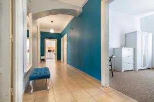 a hallway with blue walls and a blue ottoman at Spacious Apartments Zyblikiewicza Street in Krakow