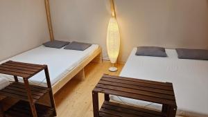 a room with two beds and a chair and a lamp at fitneXX Zelt-Dorf in Balsthal