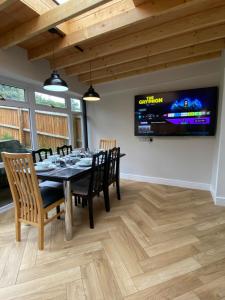 comedor con mesa, sillas y TV en Spacious 4 Bedroom House in Northampton by HP Accommodation - Free Private Parking en Northampton