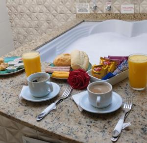 a table with two cups of coffee and a tray of food at Lina Motel Tatuapé in São Paulo