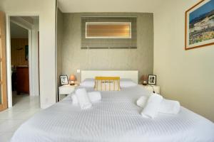 ein Schlafzimmer mit einem großen weißen Bett mit weißen Kissen in der Unterkunft La Dune *30m de la mer*parking privé* in Ploemeur