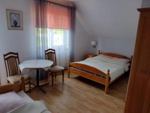 a bedroom with a bed and a table and chairs at Zajazd nad stawami in Uherce Mineralne (7)