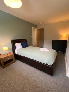 a bedroom with a large bed and a television at Spacious 4 Bedroom House in Northampton by HP Accommodation - Free Private Parking in Northampton