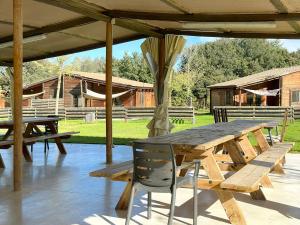 a wooden picnic table and chairs under a pavilion at Càmping Rural Montori in Ultramort