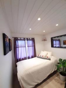 - une chambre avec un lit blanc et des rideaux violets dans l'établissement Cosy family home with pool, à Grimstad