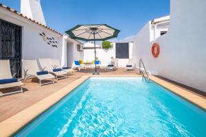 - une piscine avec des chaises et un parasol à côté d'un bâtiment dans l'établissement Villa Belize by Algarve Vacation, à Albufeira