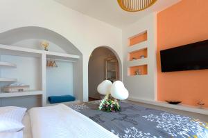 a bedroom with a bed and a flat screen tv at Caldera Butterfly Villas in Fira