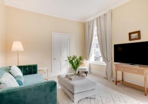 ein Wohnzimmer mit einem blauen Sofa und einem Flachbild-TV in der Unterkunft Vane Hill Crest in Torquay