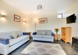 a living room with two couches and a tv at Teign Cottage in Broadhempston