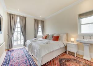 a white bedroom with a large bed and a sink at Vane Hill Crest in Torquay