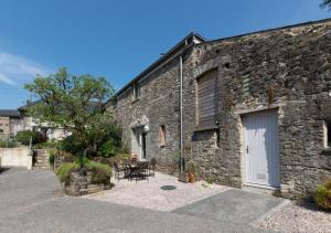 an old stone building with a table and a patio at Teign Cottage in Broadhempston