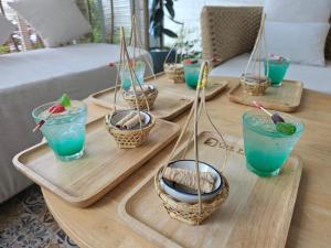 una mesa con cuatro bandejas con bebidas y cestas azules en The Pin Boutique Pool Villa Krabi, en Ao Nang Beach