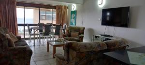 a living room with chairs and a television and a table at Holiday unit 54 Eden Dunes in Shelly Beach