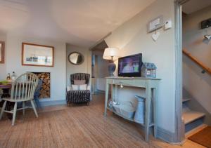 sala de estar con mesa y TV. en Compass Cottage Shaldon en Shaldon