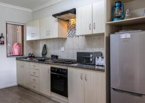 a kitchen with wooden cabinets and a stainless steel refrigerator at Hartenbos Lagoon Resort by Dream Resorts in Hartenbos
