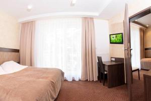 a hotel room with a bed and a desk and a window at Villa Amelia in Niechorze
