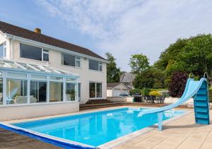 a swimming pool with a slide in front of a house at The Firs in Churston Ferrers