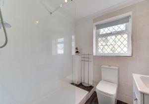 a white bathroom with a toilet and a window at Abbey Mews in Torquay