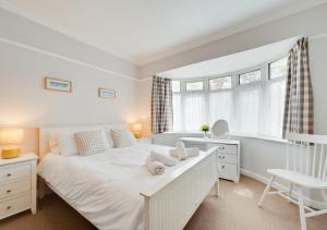 a white bedroom with a white bed and a chair at Preston Down in Paignton