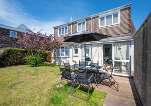 a patio with a table and chairs and an umbrella at Preston Down in Paignton