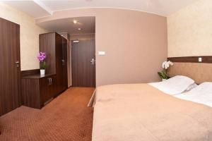 a hotel room with a large bed and flowers at Villa Amelia in Niechorze