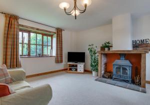 a living room with a fireplace and a tv at Luccombe Barn in Exminster
