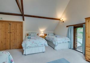 a bedroom with two beds and a window at Luccombe Barn in Exminster