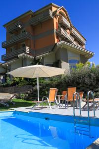 uma piscina com cadeiras e um guarda-sol e um edifício em Hotel Berghof Amaranth em Wilderswil