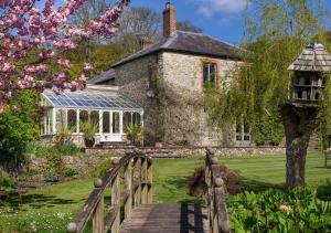 an old stone house with a bridge and a garden at Hutchinghayes Farmhouse in Honiton