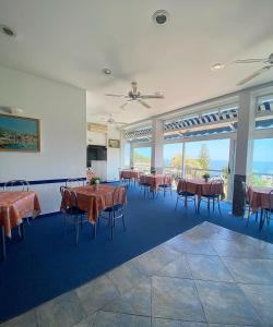 a dining room with tables and chairs and large windows at Hotel Cyrnea in Bastia