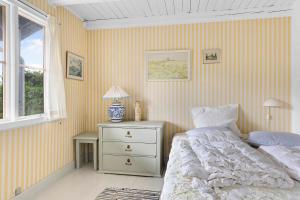 um quarto com uma cama e uma mesa com um candeeiro em Summerhouse At The Beach em Rørvig