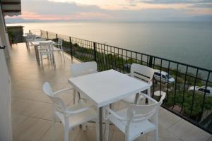 a white table and chairs on a balcony with the ocean at LakeFront House in Shirokë