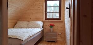 a small bed in a wooden room with a window at DOMEK AGA in Kruklanki