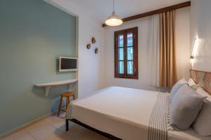a bedroom with a bed and a chair and a window at Bouti Ayvalık in Ayvalık