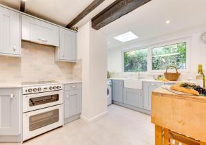 a kitchen with white cabinets and a sink at Chart Cottage in Beer