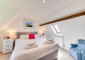 a bedroom with a white bed and a blue chair at Chart Cottage in Beer