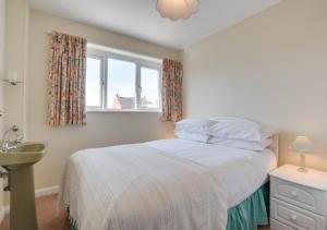 a bedroom with a bed with a window and a sink at Farthings in Salcombe Regis