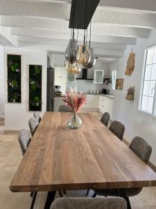 a wooden table with chairs and a vase of flowers on it at Villa Les Folies - magnifique jardin avec piscine in Le Beausset