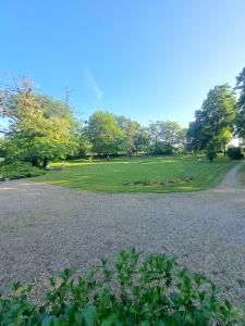 ein Park mit einem Grasfeld und Bäumen im Hintergrund in der Unterkunft Le manoir d'Estiveaux in Le Châtelet