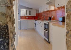 a kitchen with white appliances and red tile at Harmony Cottage in Seaton