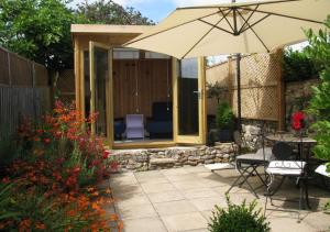 a patio with an umbrella and a table and chairs at Harmony Cottage in Seaton