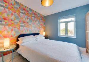 1 dormitorio con cama blanca y pared colorida en Windy Ridge, en Colyton